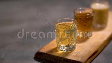 三个酒精芳香的酒，美味的服务停留在木桌上，准备饮用。 相机从左移
